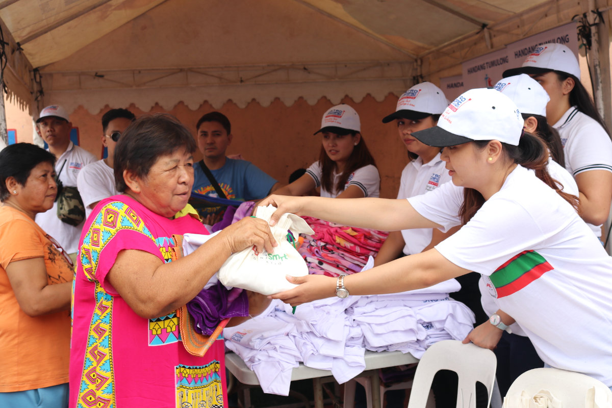 A beneficiary receives the hygiene kit from an employee-volunteer.