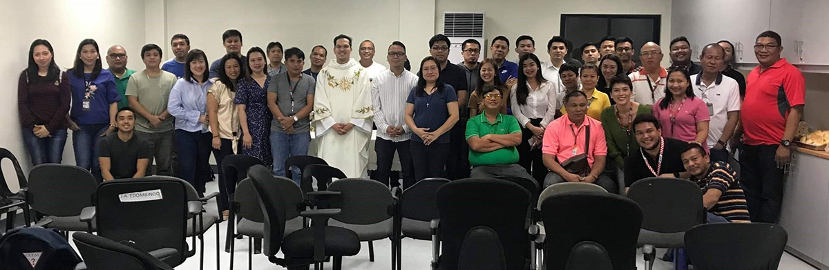 Employees pose for a souvenir photo with the celebrant after the Mass at PLDT Iloilo.