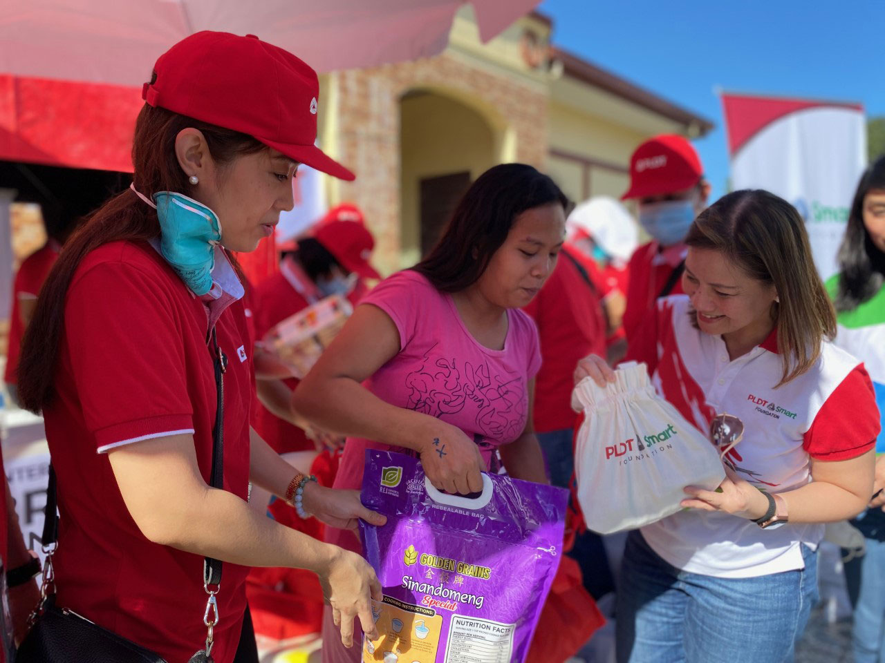 PLDT Community Relations Head Katherine Diaz De Rivera and PLDT-Smart Foundation President Esther Santos give relief packs to a Taal Volcano eruption evacuee on Thursday at the Sto. Tomas North Central School in Sto. Tomas, Batangas.
