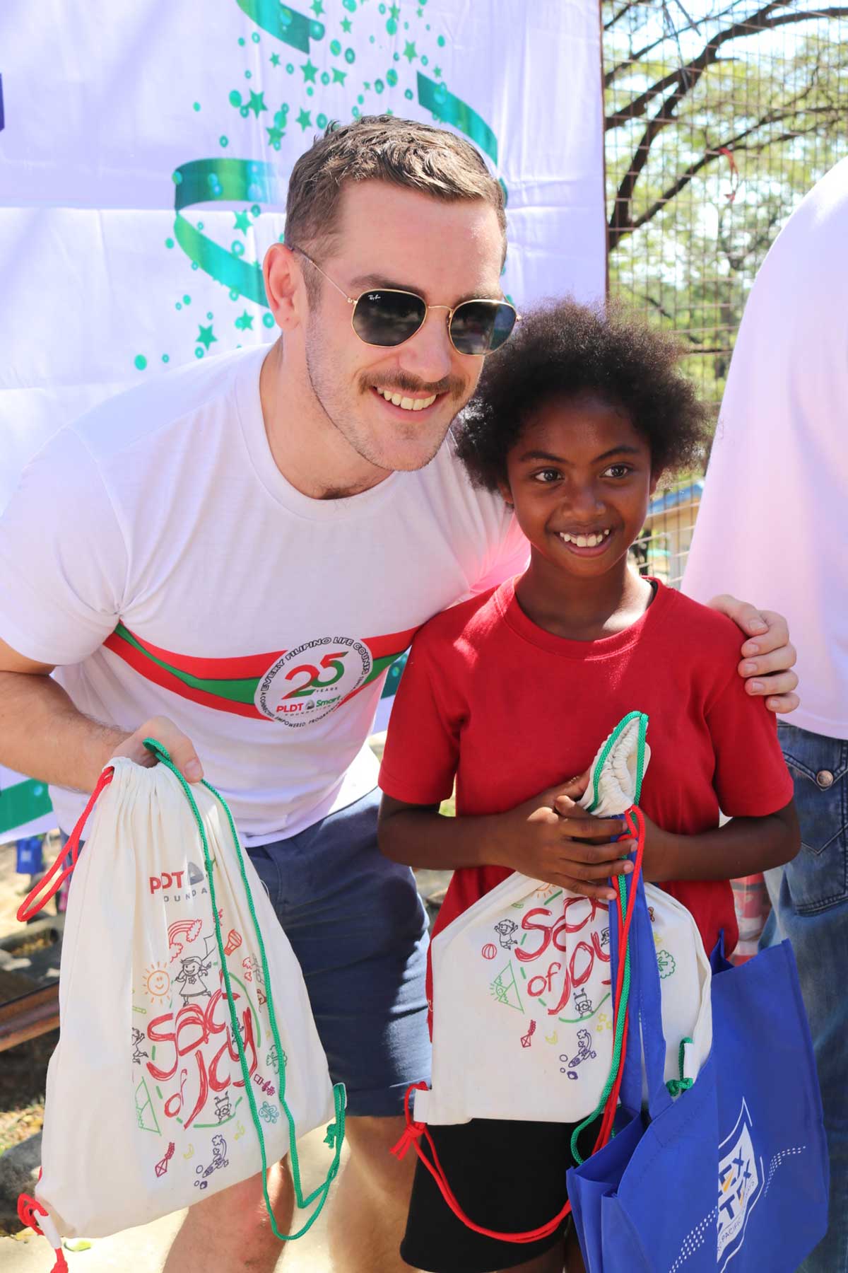 Renoir Group’s Luke Callachan distributes a Sack of Joy bag to a kid in the Aeta Community in Porac, Pampanga.