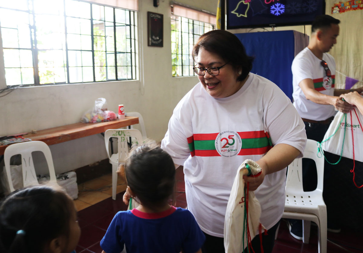 PLDT FVP for Tax Management Atty. Cris Guhit helps distribute a PLDT Sack of Joy bag during the outreach activity.